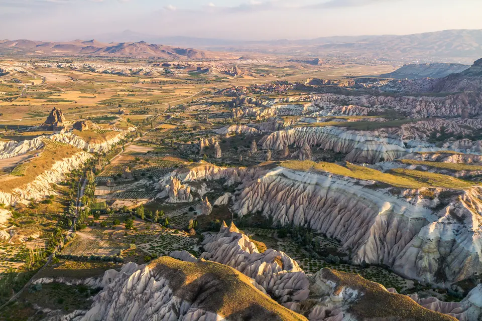 An aerial view of eroded ridges and valleys in golden light in Cappadocia.