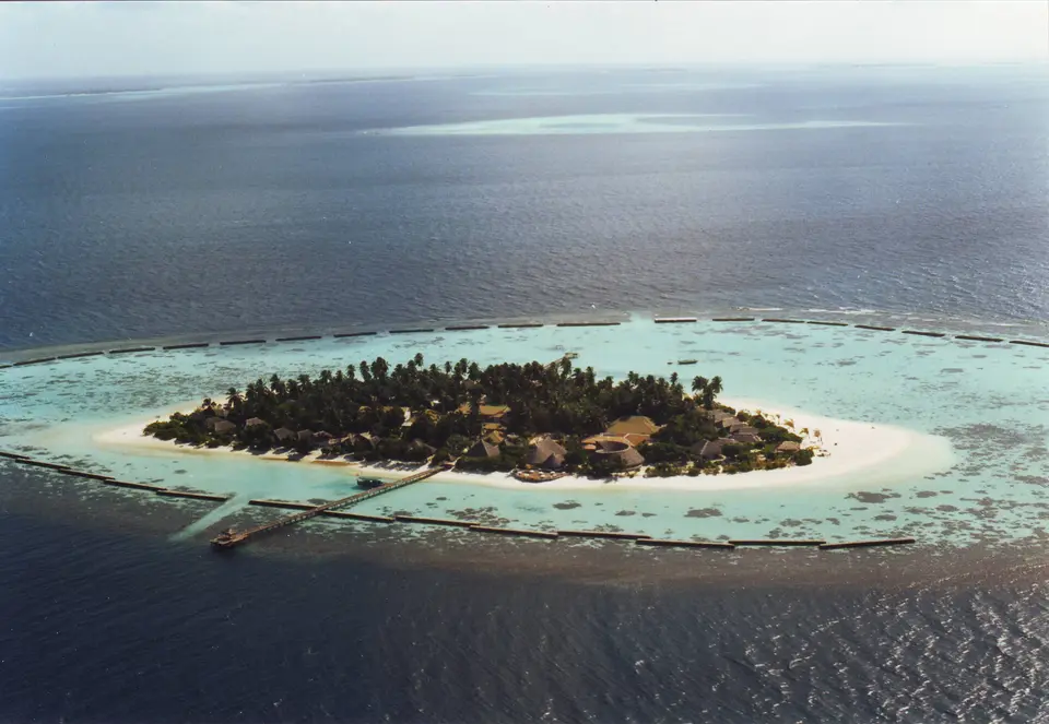 A small palm-covered island ringed by white sand and shallow turquoise water.