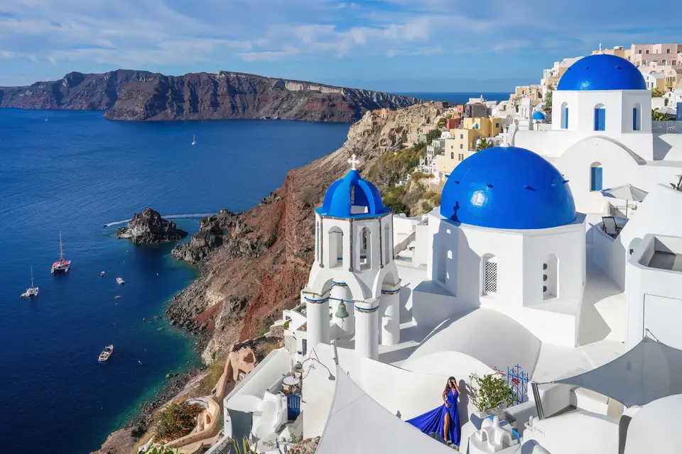 White buildings with blue domes on a cliff above a deep blue sea in Oia, Santorini.