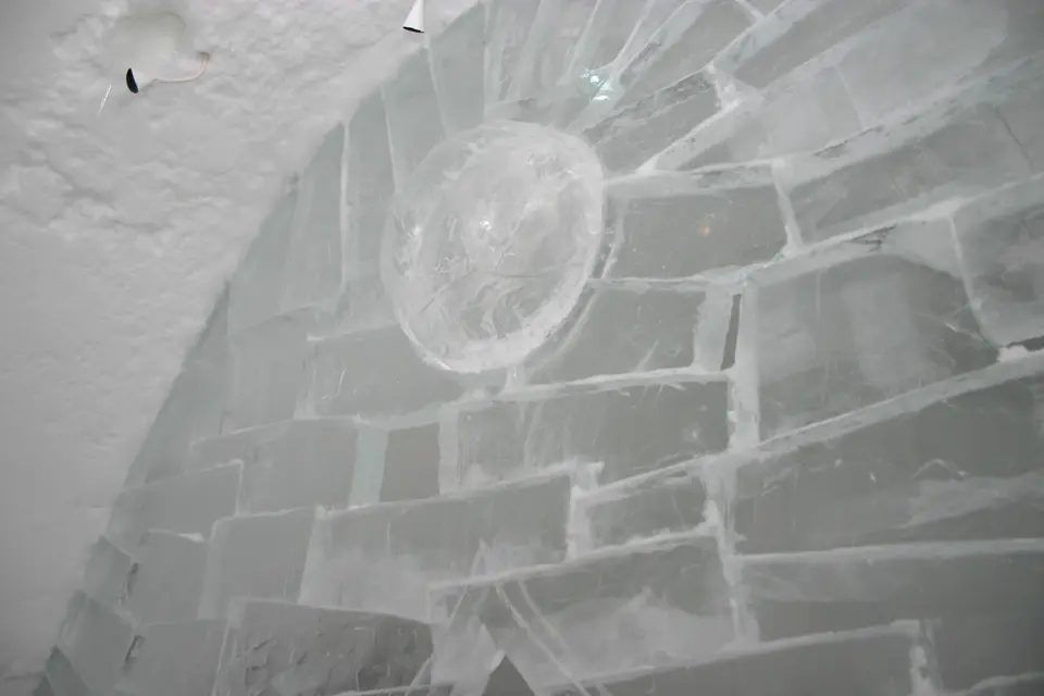 A vaulted corridor in a hotel built of ice blocks with a round carved feature in the wall.
